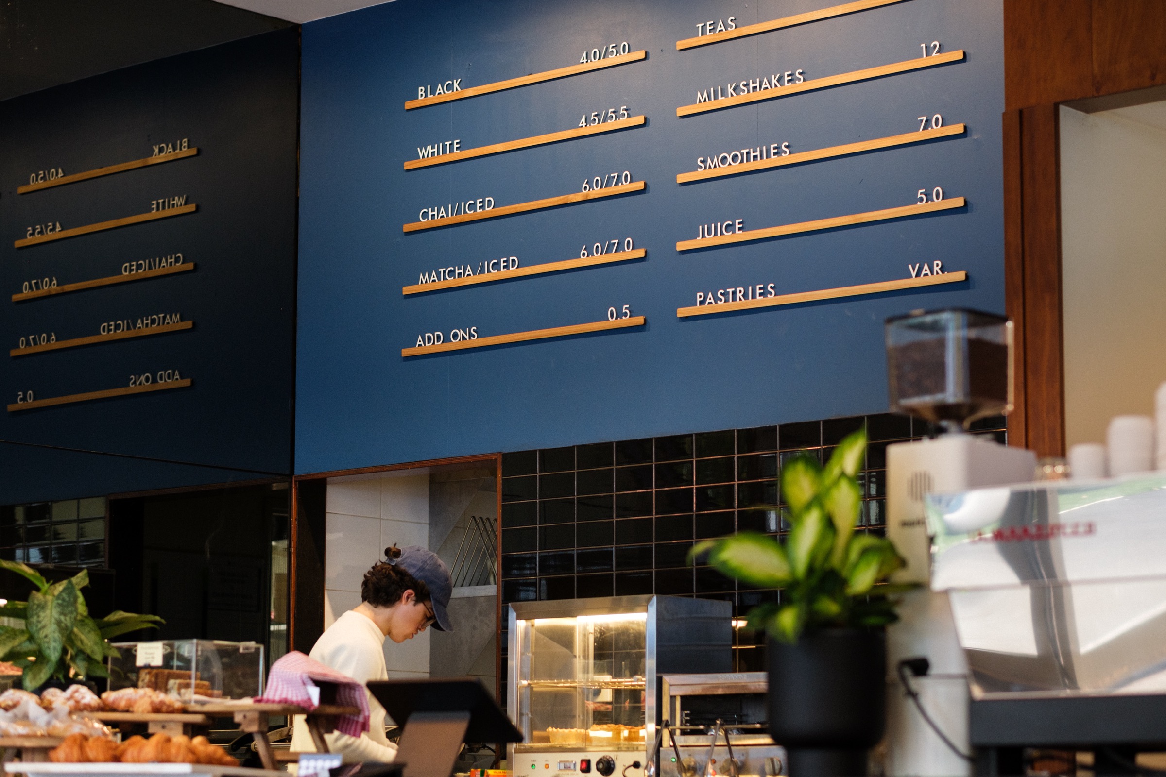 Forum Coffee menu wall and barista at the counter